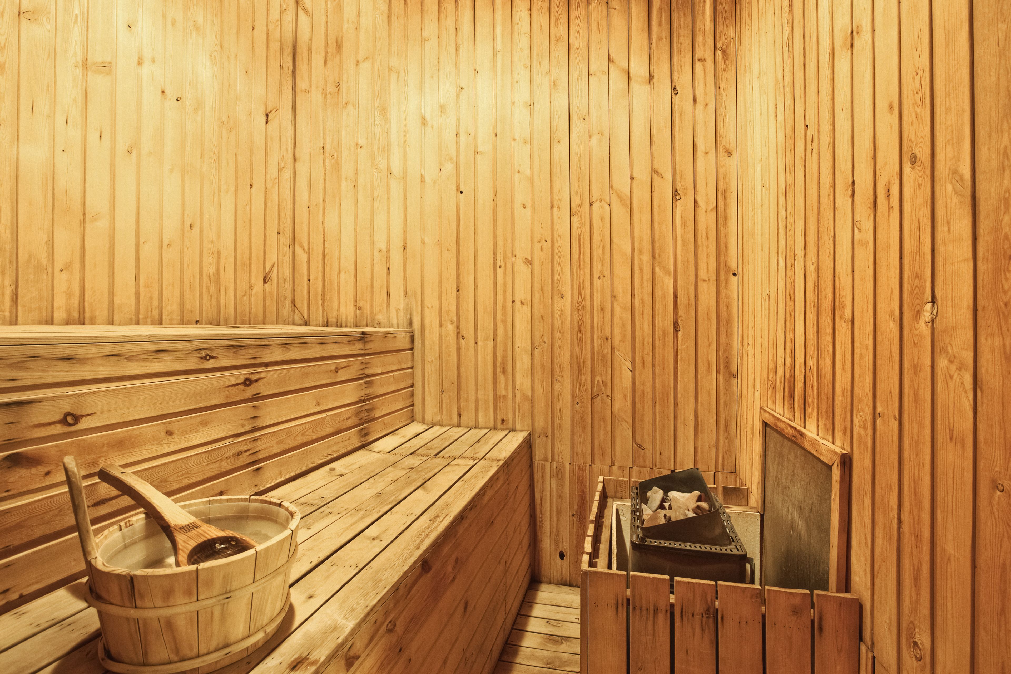 A wooden sauna with benches and a wooden bucket.