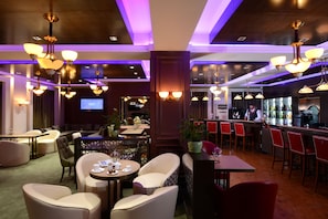 A modern lounge area with multiple seating options, including sofas and chairs, and a bar area with stools. - Kempinski Hotel Khan Palace (Ulaanbaatar)