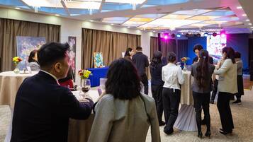 A formal event in a well-lit room with tables, attendees, and a stage with lighting.