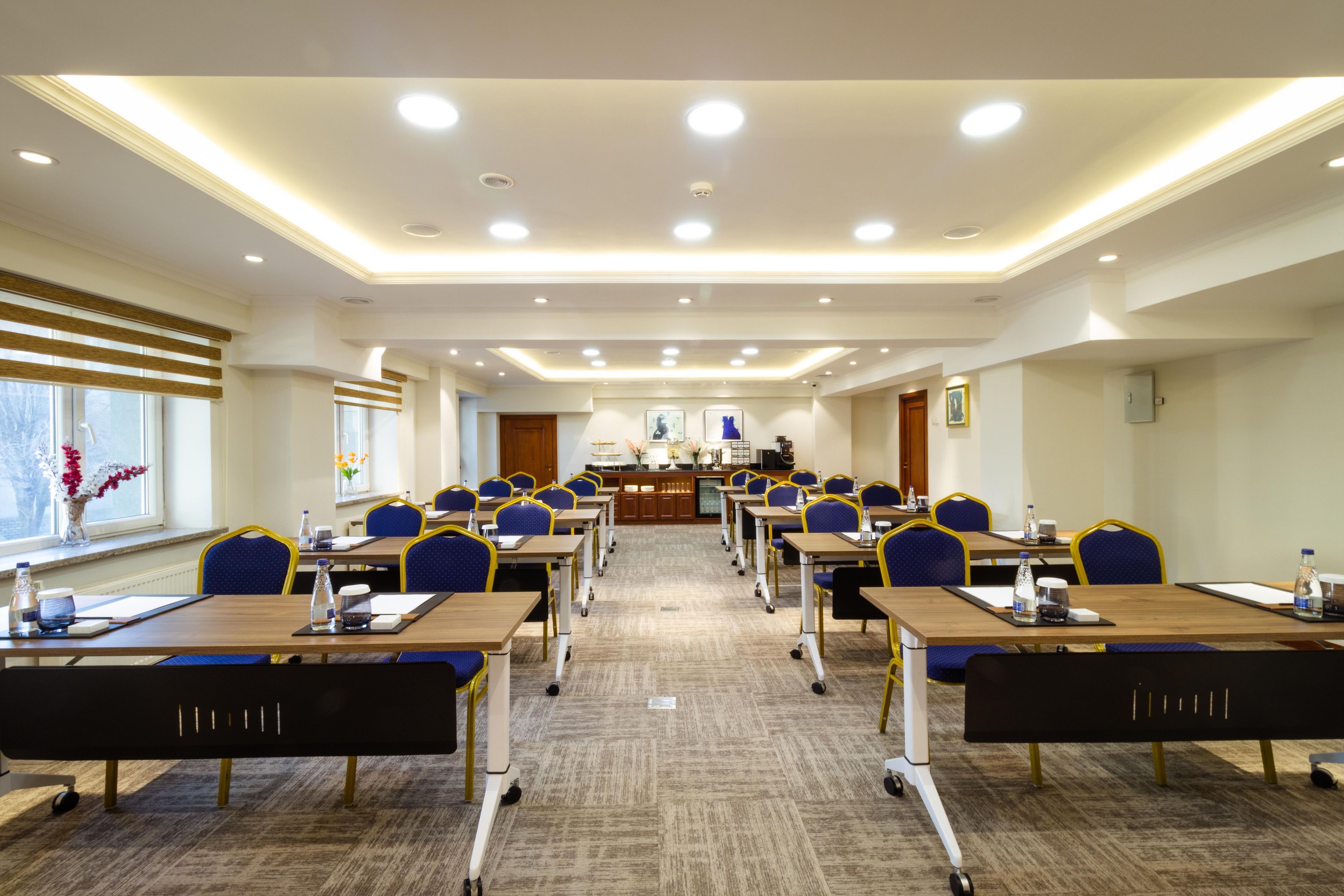 A conference room with multiple tables and chairs, equipped with water bottles and nameplates.