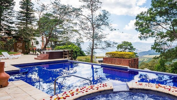 Uma banheira de hidromassagem com vista para as montanhas, rodeada por um espaço de estar com espreguiçadeiras e um deck de madeira.