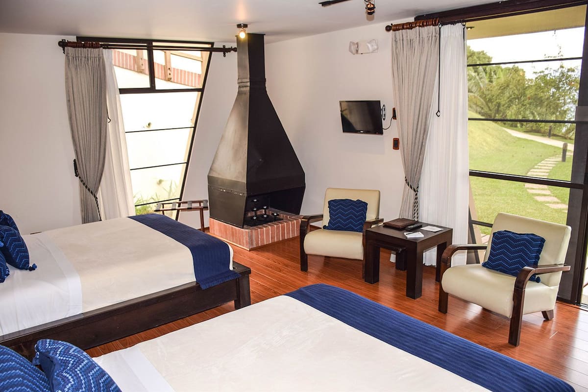 A hotel room with a large bed, a seating area with a table, and a fireplace.