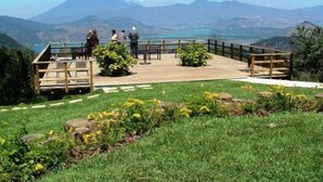 Um deck de madeira com bancos, com vista para uma paisagem montanhosa.