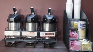 A coffee station with three Bunn coffee machines, a hot water dispenser, and a cream dispenser.