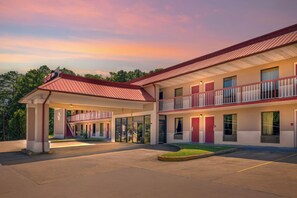 Un motel con entrada cubierta, varias habitaciones y techo rojo.