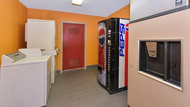 Un couloir avec un distributeur automatique, une porte et un réfrigérateur.