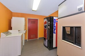 Ein Flur mit einem Getränkeautomaten, einer Tür und einem Kühlschrank.