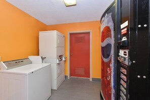 A laundry room with a washer and dryer, a red door, and a vending machine. - Red Roof Inn Cartersville–Emerson/LakePoint North (Cartersville)
