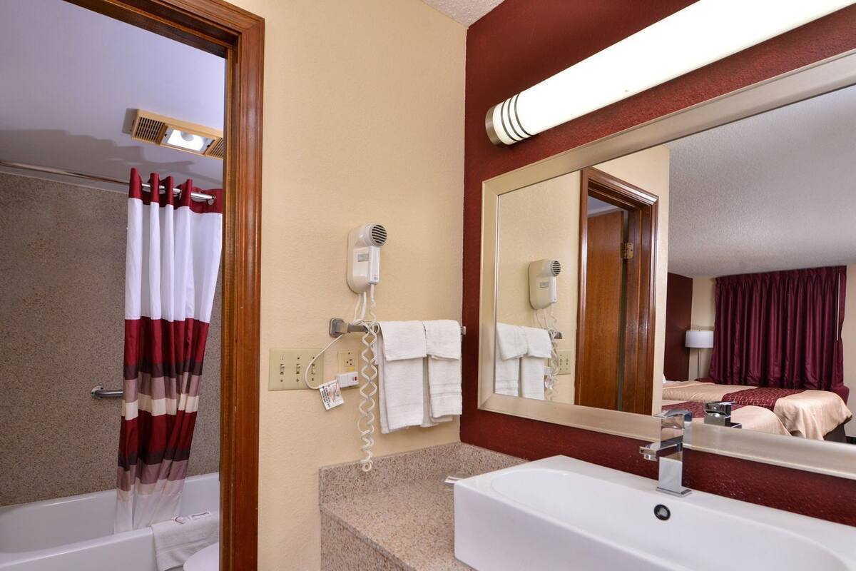 A bathroom with a bathtub, a shower, a sink, and a mirror.