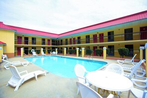 A hotel with a central pool, multiple balconies, and outdoor seating. - Red Roof Inn Cartersville–Emerson/LakePoint North (Cartersville)