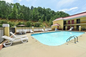 A swimming pool with lounge chairs and umbrellas, surrounded by a fenced area with a building in the background. - Red Roof Inn Cartersville–Emerson/LakePoint North (Cartersville)