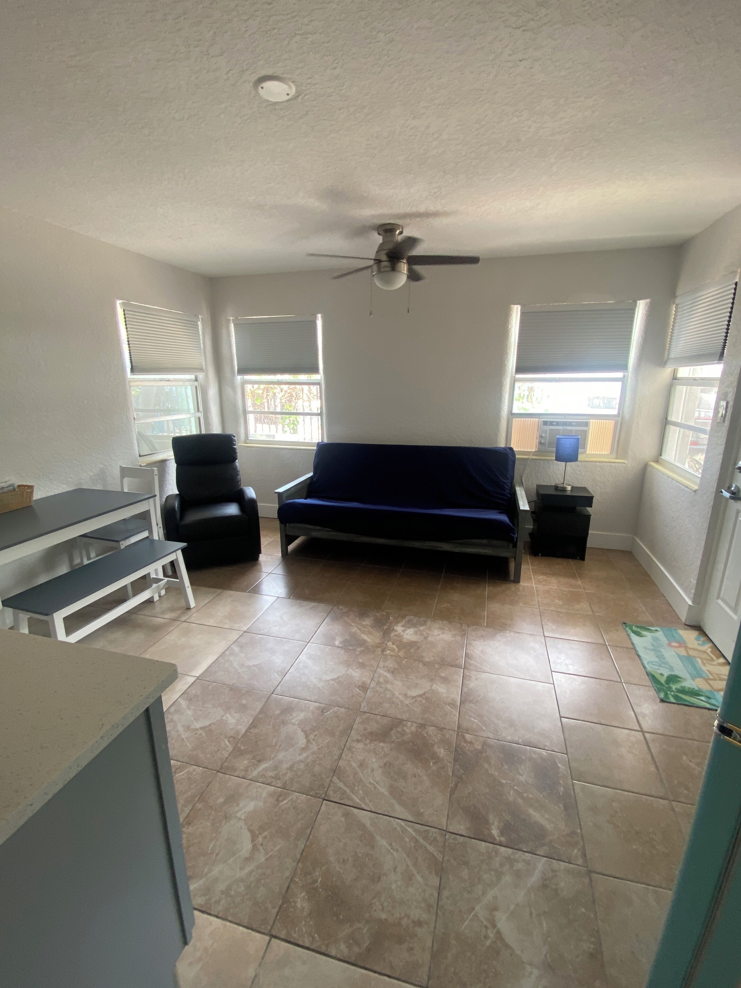 Une pièce comprenant un lit, un bureau, une chaise et un ventilateur de plafond.