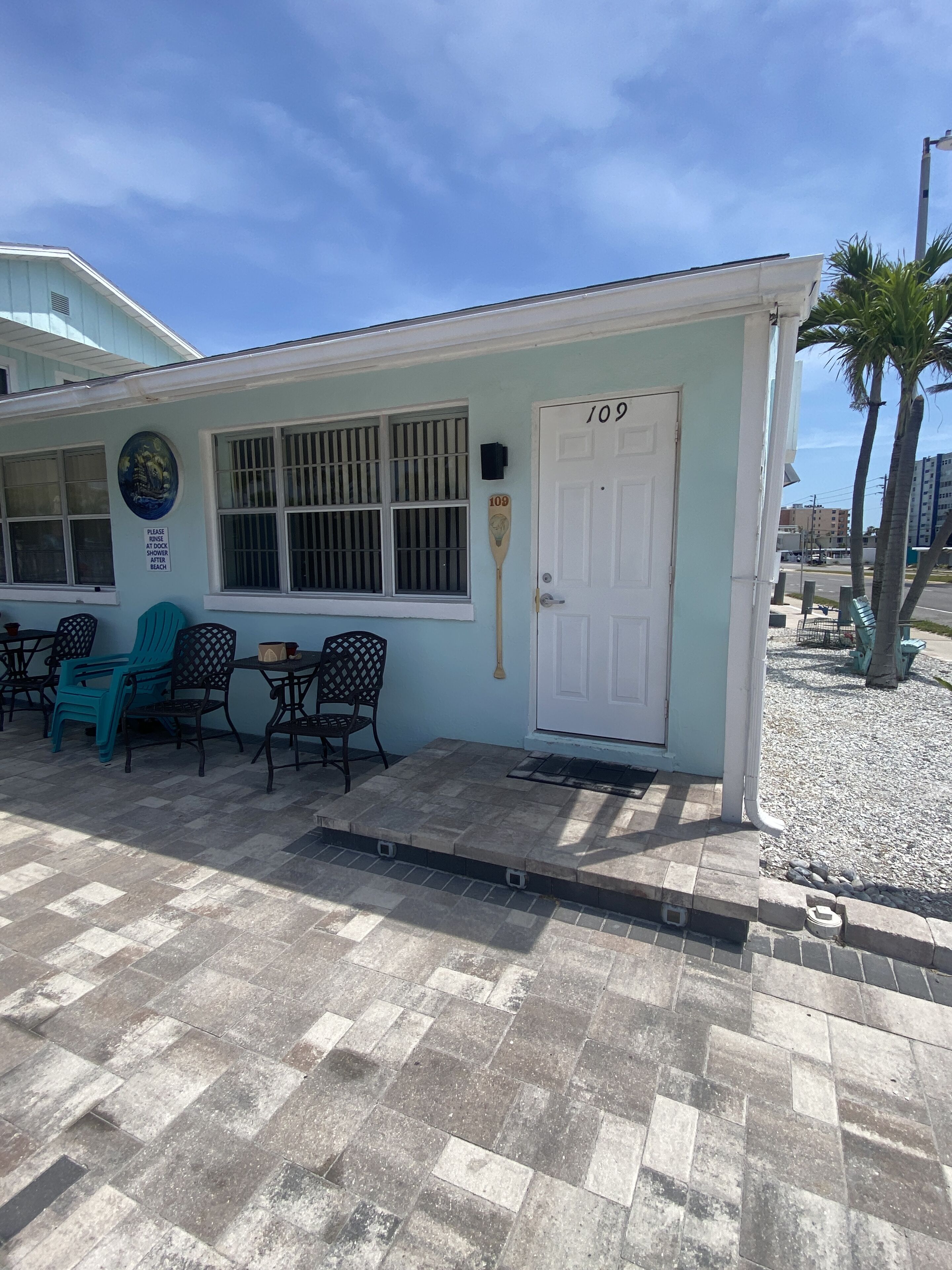 A small building with a white door marked "109", a window with bars, and a paddleboard leaning against the wall.
