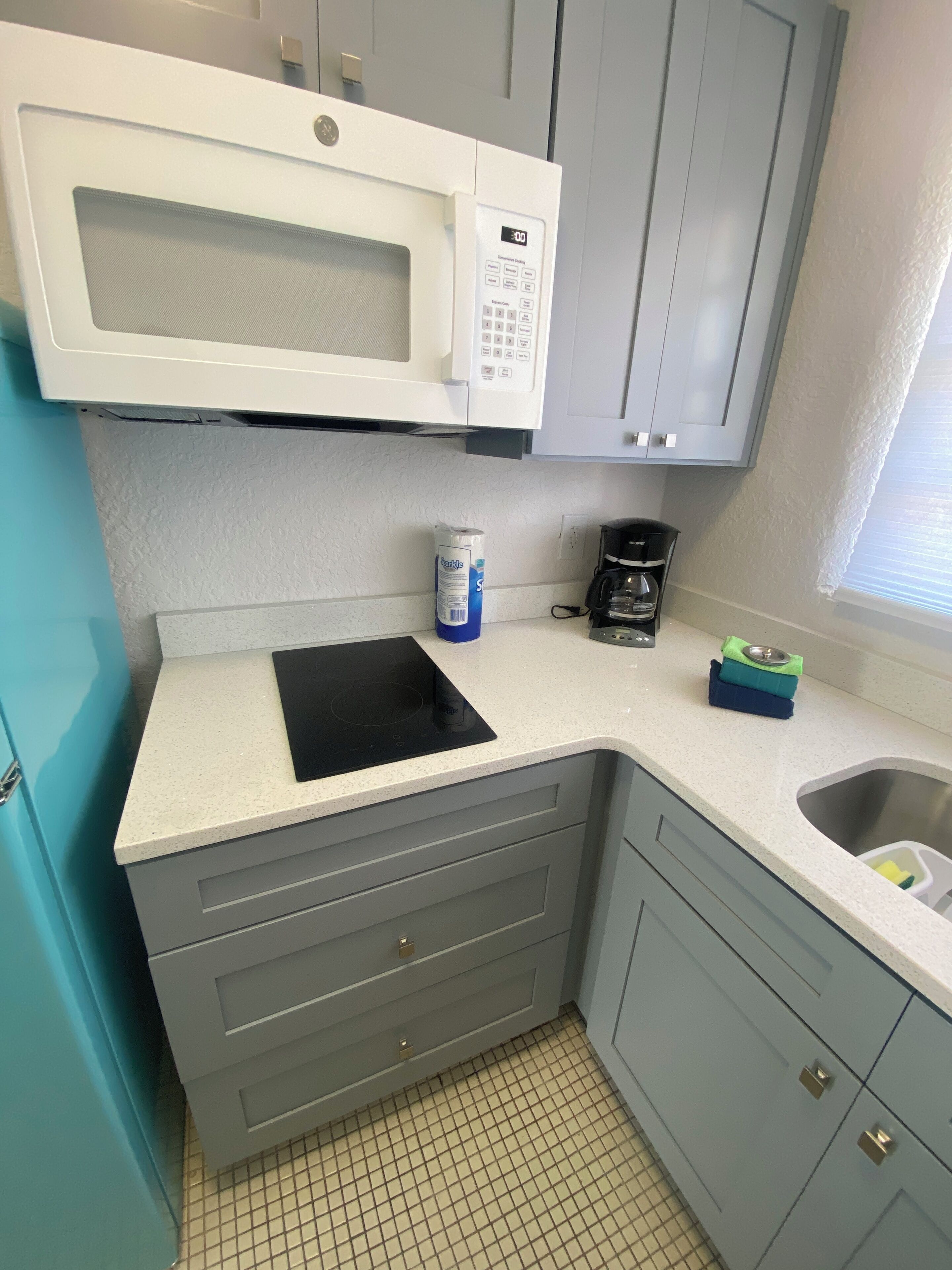 A kitchen with a microwave, coffee maker, and a sink.