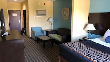 Quarto de hotel com cama, escrivaninha, poltrona, sofá e abajur.