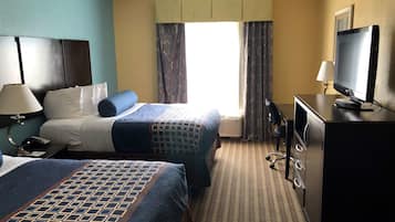 Une chambre d’hôtel avec deux lits, un bureau avec un ordinateur, une télévision et une fenêtre avec des rideaux.