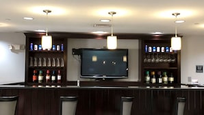 A bar area with a flat-screen TV, shelves with bottles, glasses, and a sign. - Best Western Plus Goodman Inn & Suites (Horn Lake)