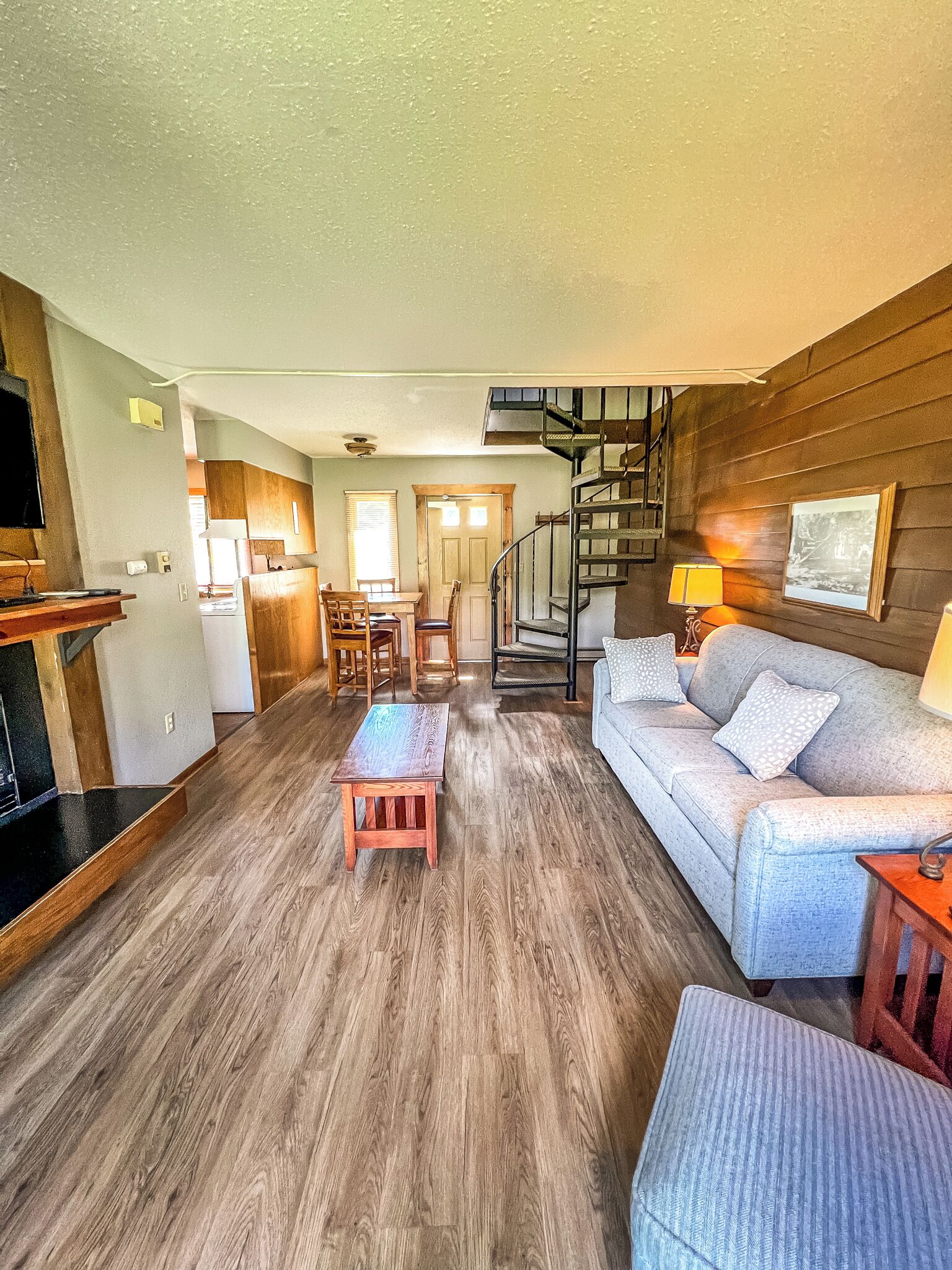 Un vaste espace de vie doté d’un plancher en bois, d’un canapé, d’une table basse et d’un escalier menant à un niveau supérieur.
