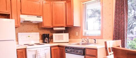 A kitchen with wooden cabinets, a white stove, a microwave, and a dishwasher.