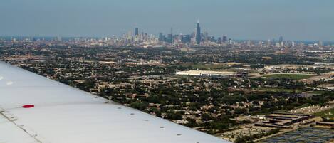 An airplane wing with a cityscape in the background.