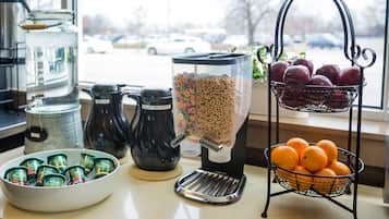 A breakfast bar with a coffee maker, cereal dispenser, and fruit basket.