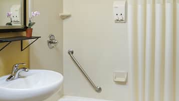 Un baño con lavamanos blanco, bañera, cortina de ducha, barandilla y espejo con luces.