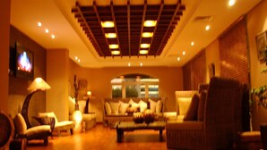 A spacious living room with a high ceiling, a large window, and a fireplace. - Spice Boutique Hotel (Salmiya)