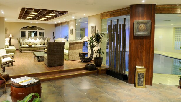 A spacious lobby with a sofa, chairs, a coffee table, and a large potted plant. - Spice Boutique Hotel (Salmiya)