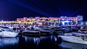 A marina at night with boats docked and a building with illuminated windows in the background. - Spice Boutique Hotel (Salmiya)