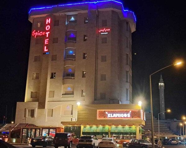 Hotellissa on neonvalomainos, jossa lukee ”Spice Hotel”, ja sen alakerrassa sijaitsee ravintola nimeltä ”Elamigos”.