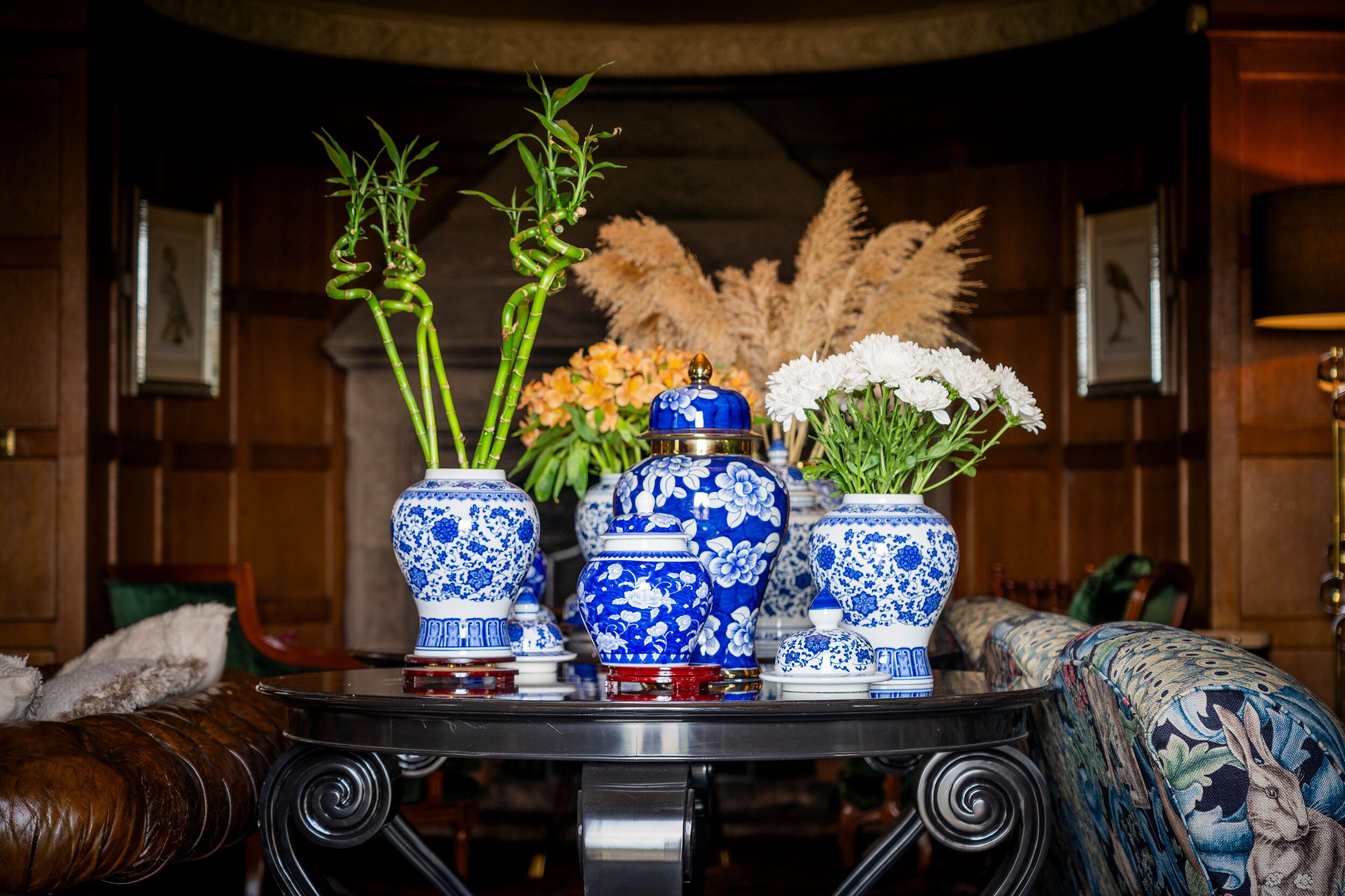 Un tavolo con tre vasi blu e bianchi decorati: uno con bambù e l'altro con fiori bianchi.
