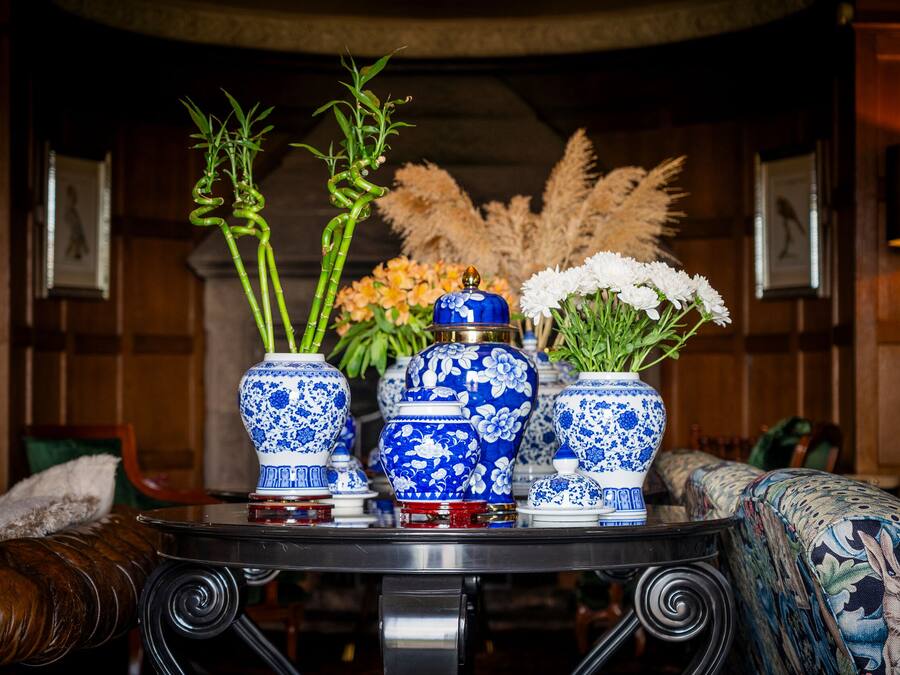 Un tavolo con tre vasi blu e bianchi decorati: uno con bambù e l'altro con fiori bianchi.