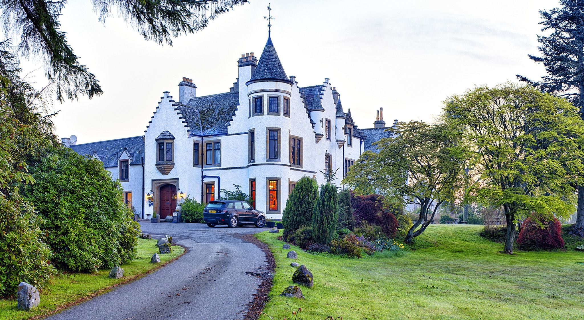 A large, white, castle-like building with multiple towers and a driveway leading to the entrance.