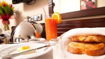 A breakfast setting with toast, butter, a glass of orange juice, and a kettle.