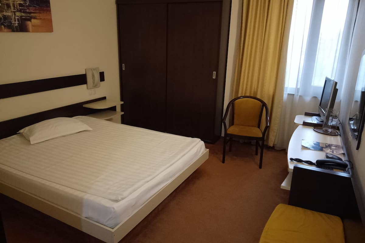 Ein Hotelzimmer mit einem Bett, einem Kleiderschrank, einem Schreibtisch mit Computer und einem Sessel.