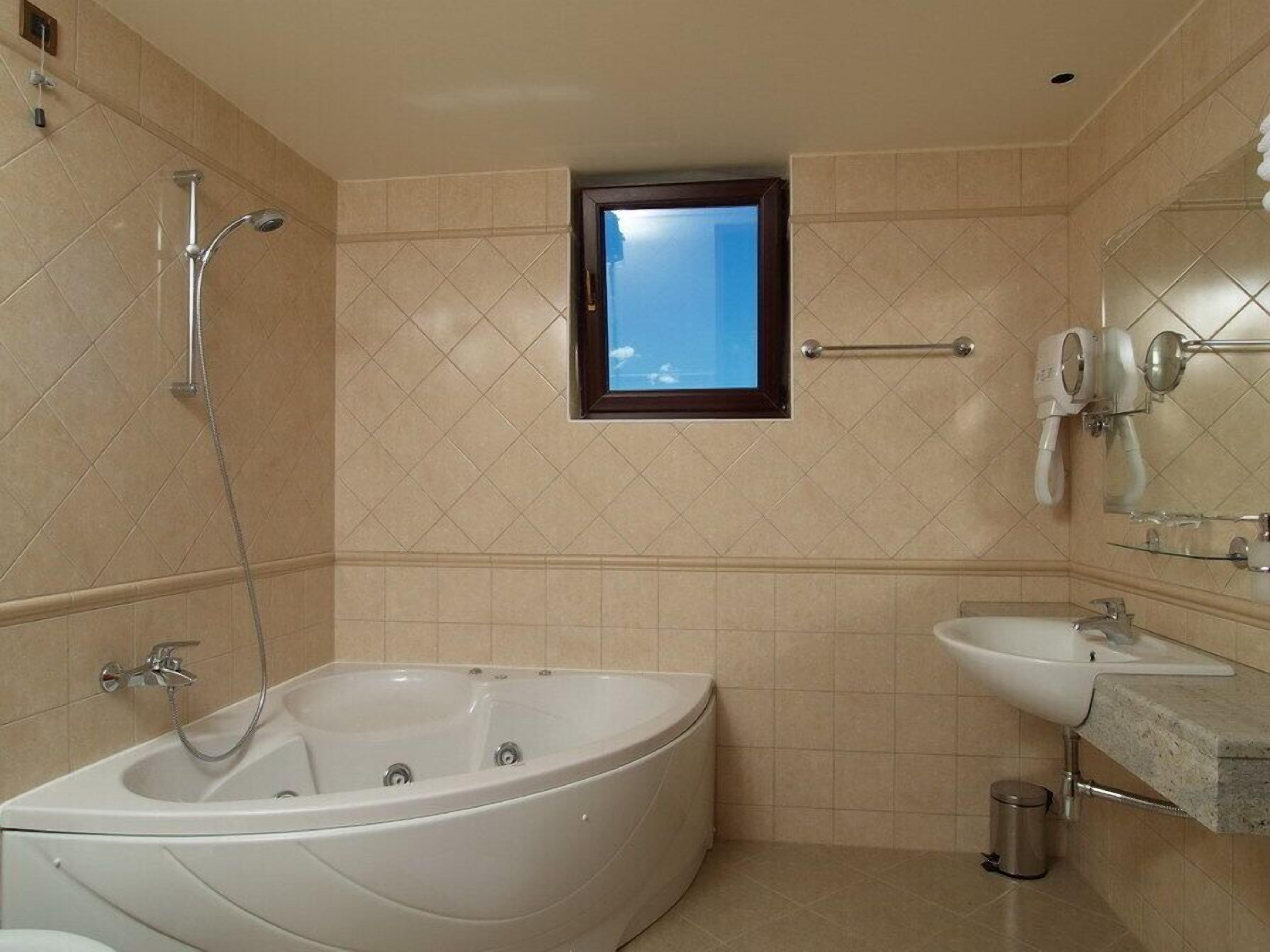 Un baño con bañera, lavamanos, ventana y ducha.