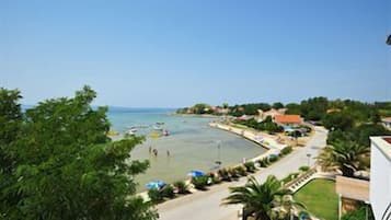 A coastal view with a beach, clear sky, and residential buildings along the shore.