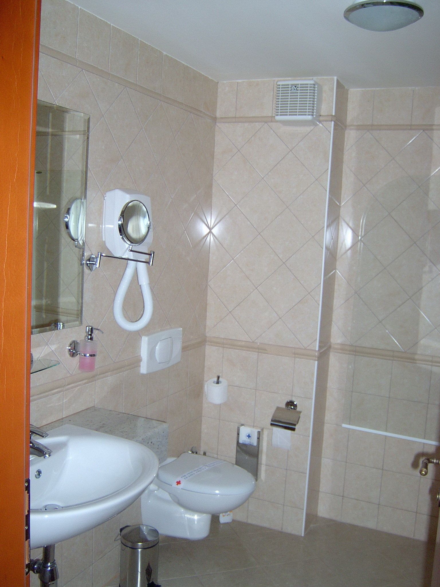 A bathroom with a sink, toilet, and mirror.