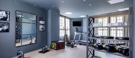 A modern gym with a treadmill, weights, and a mirror.