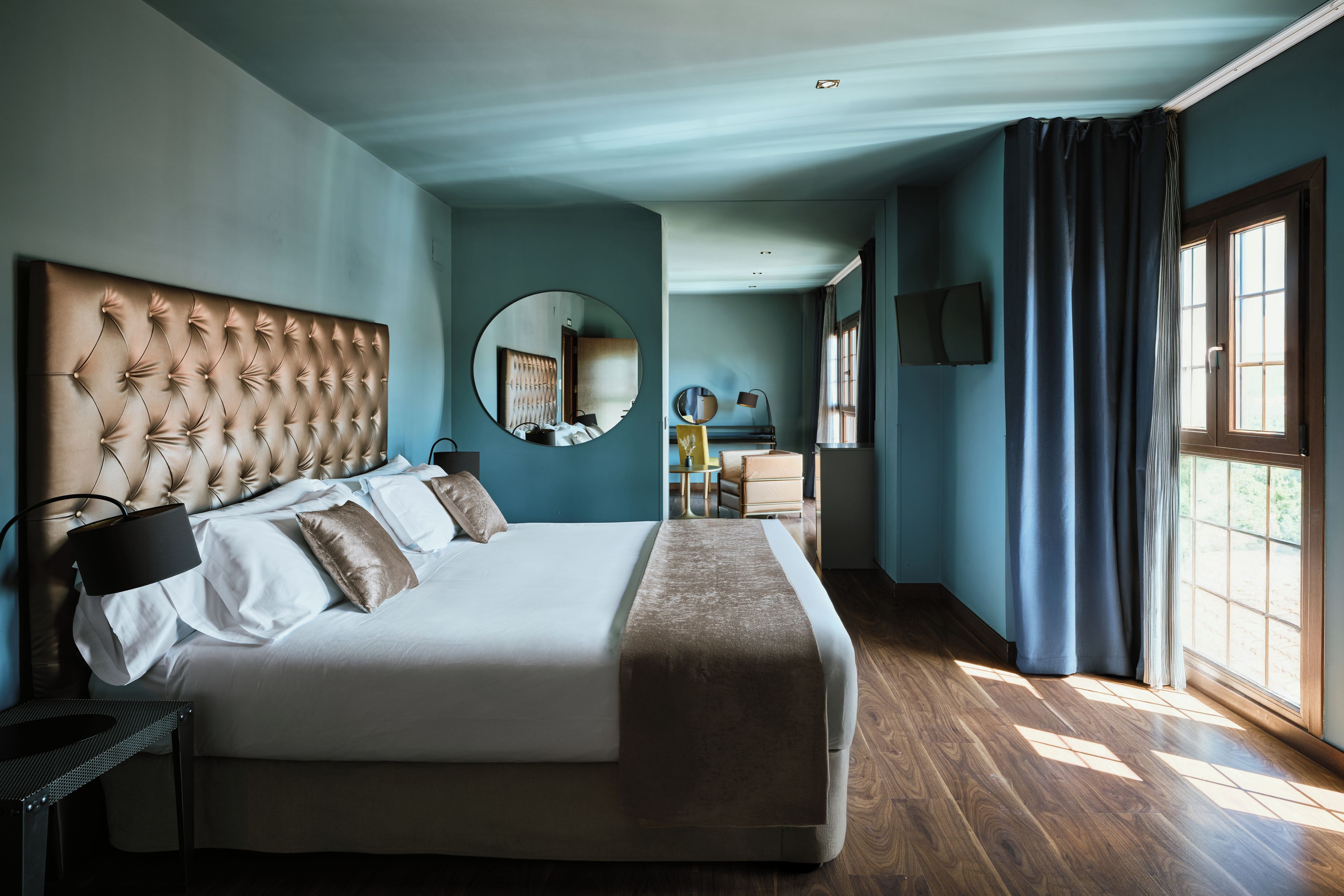 Un dormitorio amplio con una cama grande, un espejo redondo y vistas al baño.