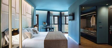 A modern hotel room with a large bed, a desk, and a walk-in closet.