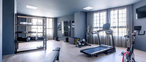 A modern gym with a bench, treadmill, stationary bike, and weight equipment.