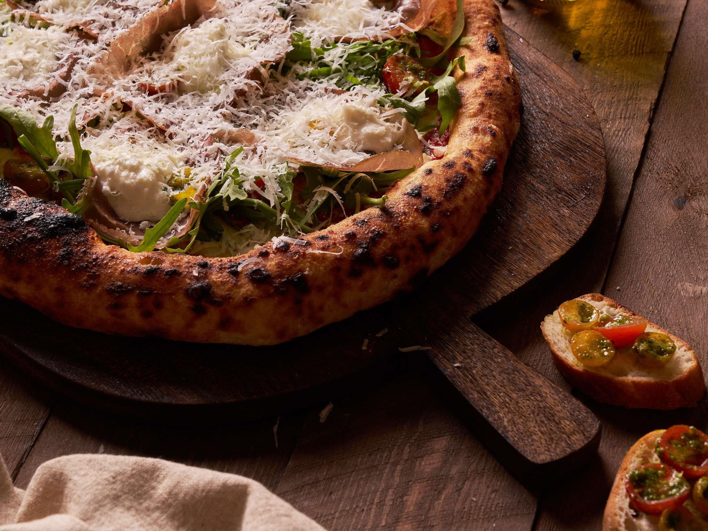 Pizza com cobertura em tábua de madeira.