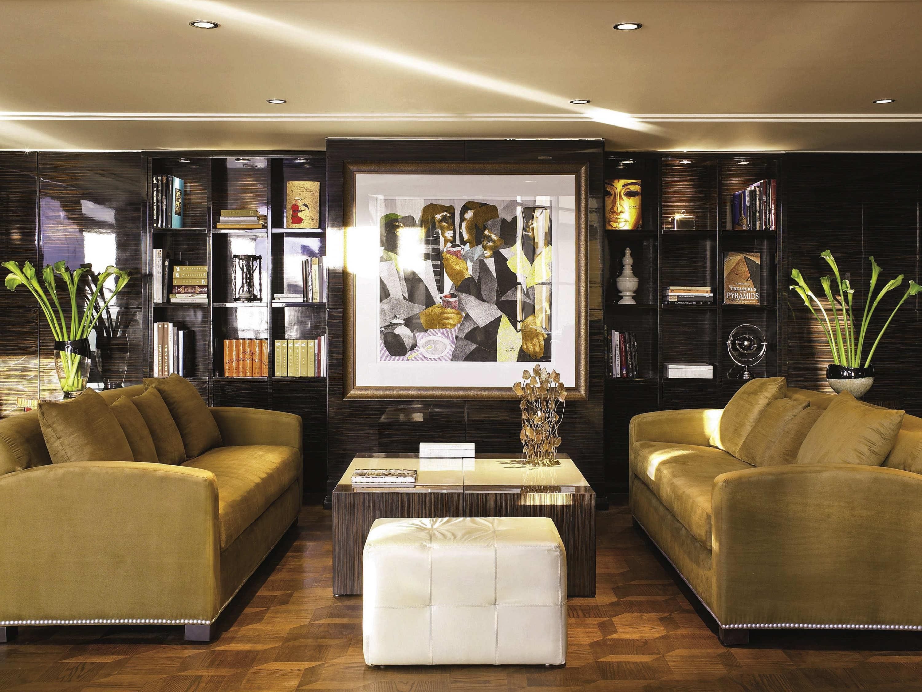 A modern living room with two sofas, a coffee table, and a bookshelf filled with books and decorative items.
