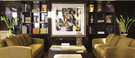 A modern living room with two sofas, a coffee table, and a bookshelf filled with books and decorative items.