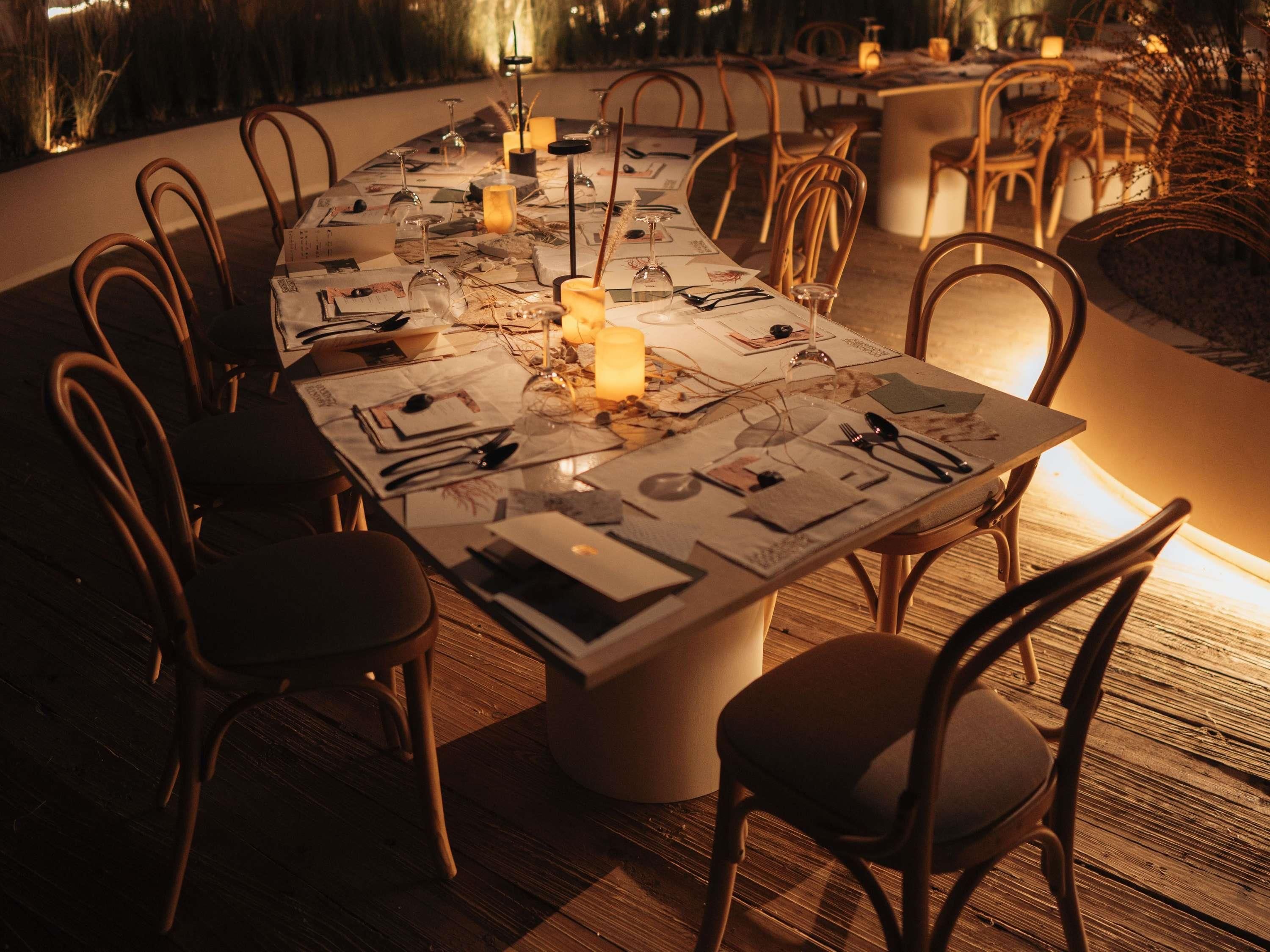 A long dining table with chairs, candles, and menus.
