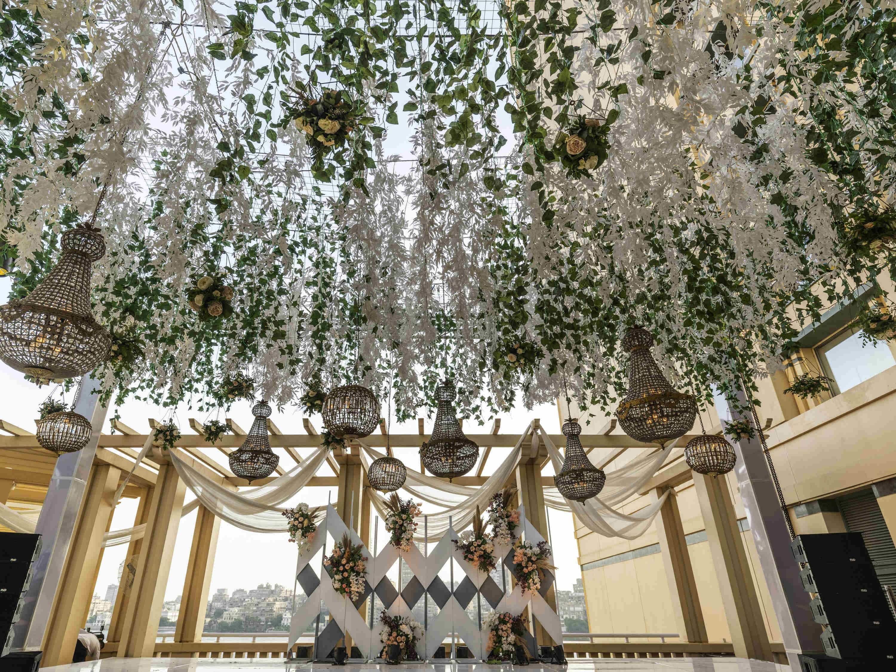Un espacio interior decorado con arreglos florales colgantes y candelabros.