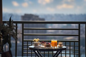 A balcony with a table set for breakfast, including pancakes, fruit, and orange juice. - Fairmont Nile City, Cairo (Cairo)