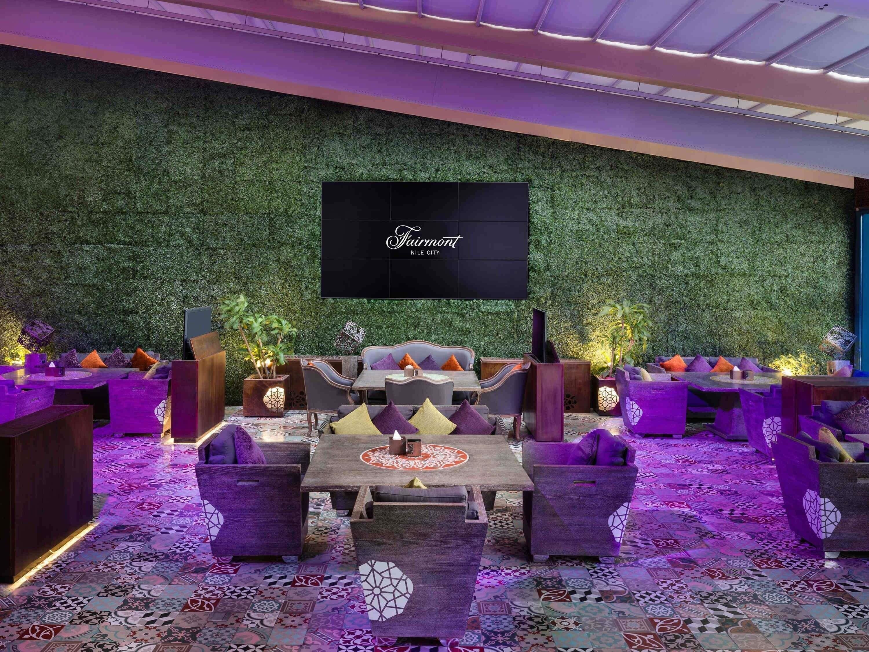 A lounge area with a green wall, a flat-screen TV, and patterned floor tiles.