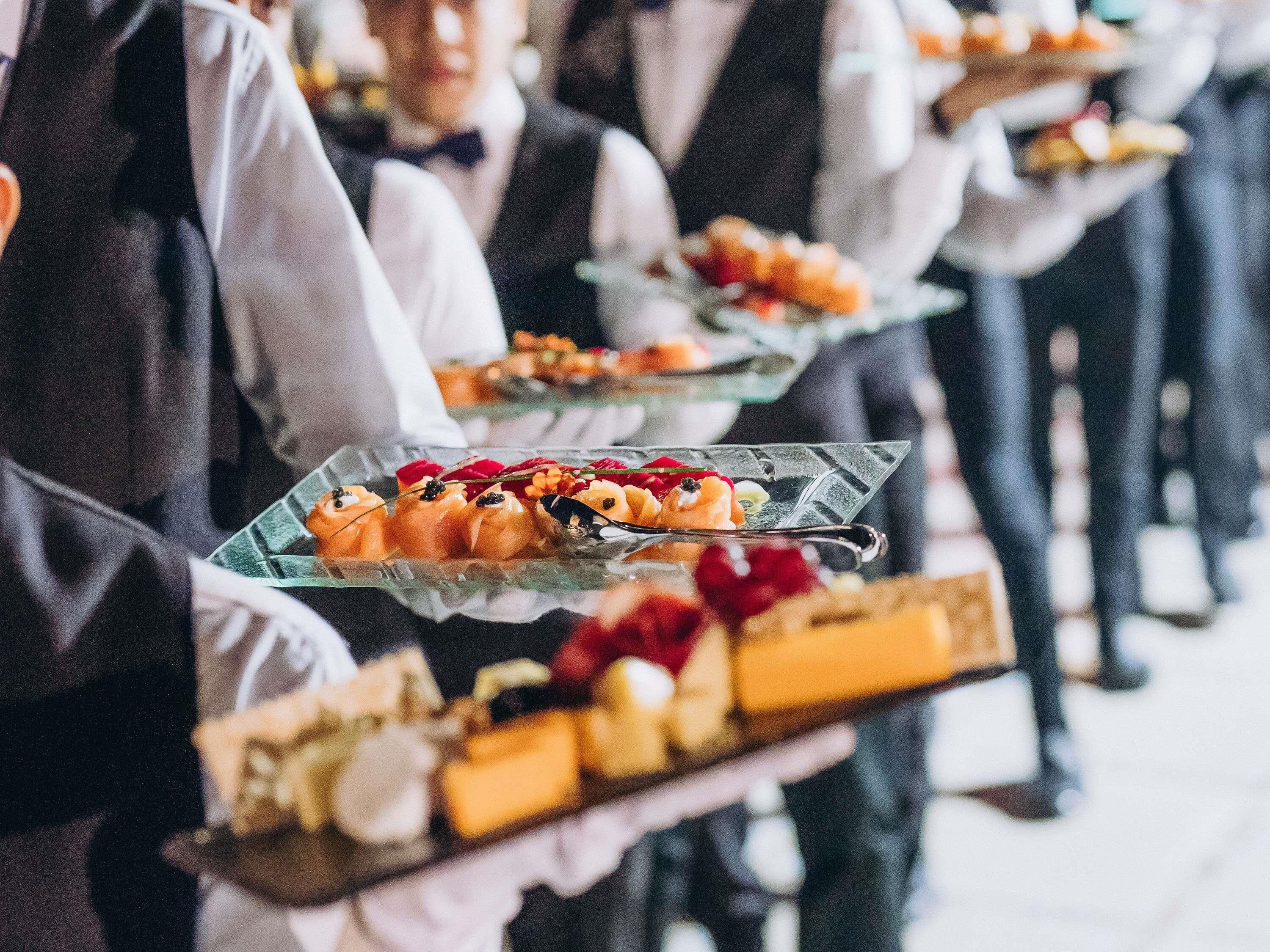 Waitstaff carrying trays of food.